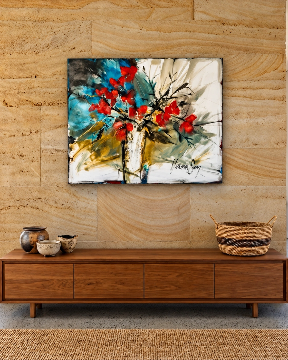 A floral painting with red flowers above a timber cabinet against a sandstone wall